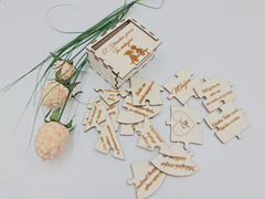 Rozložené dieliky dreveného puzzle srdca s gravírovanými vyznaniami a darčeková krabička